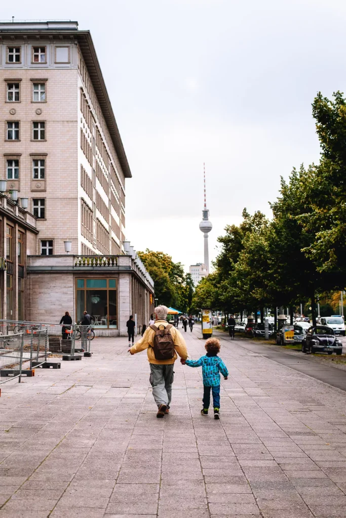 Älterer Mensch und Kind laufen Hand in Hand Richtung Berliner Fernsehturm